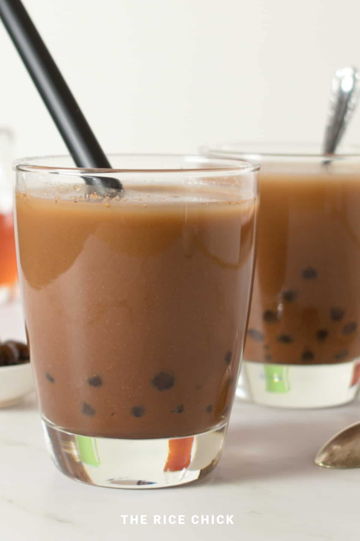 Chocolate boba in a glass with a straw.