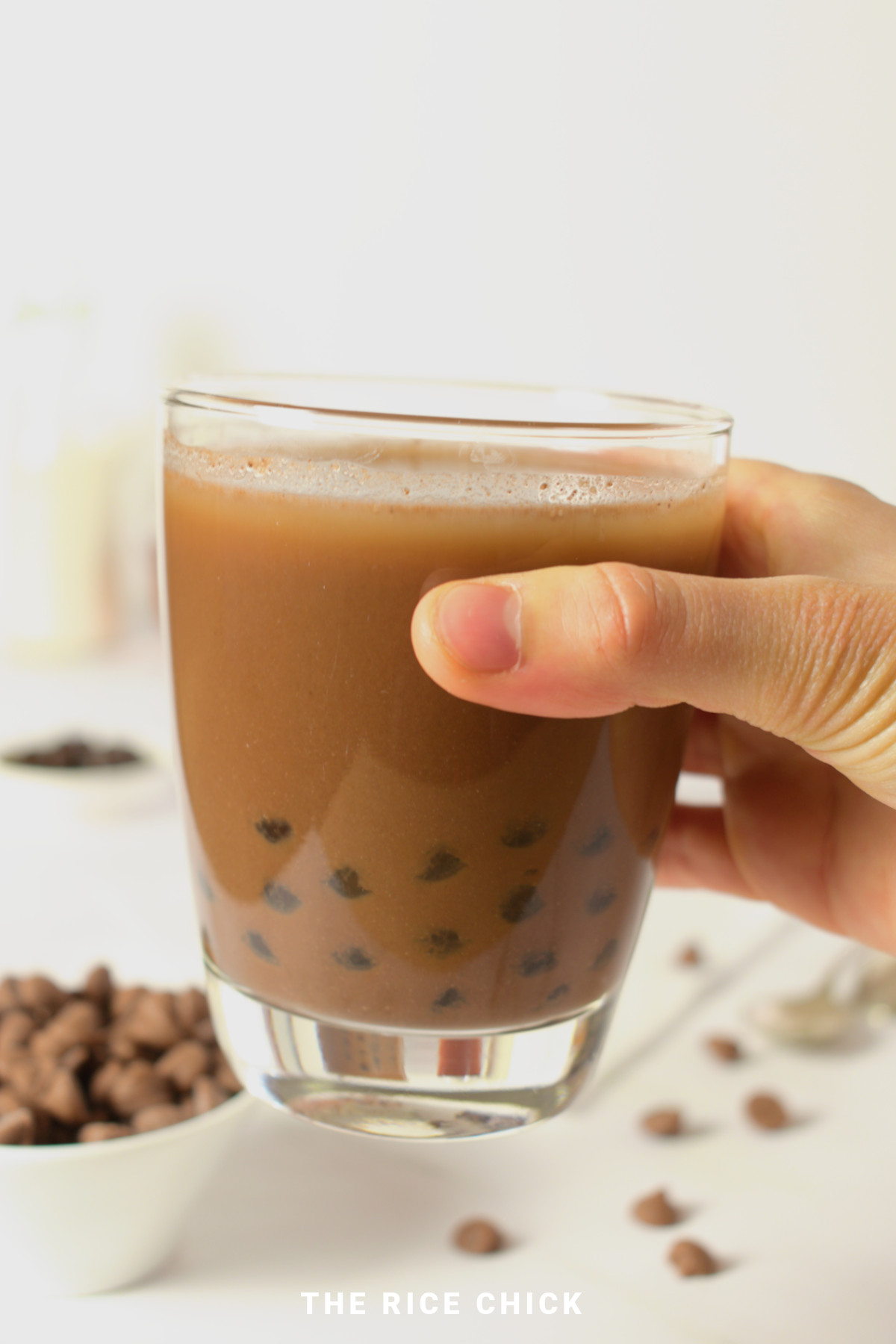 Glass of chocolate milk tea being held in a hand.