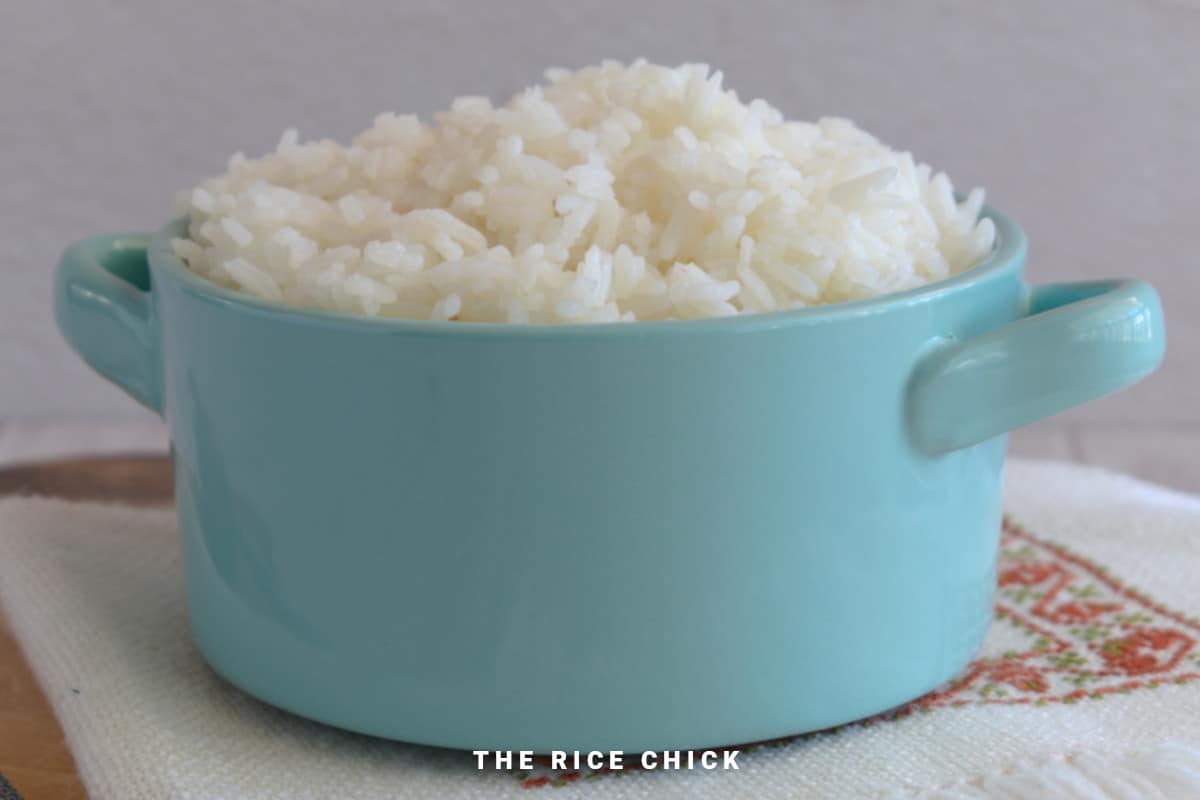Image of cooked jasmine rice in a blue bowl with handles.