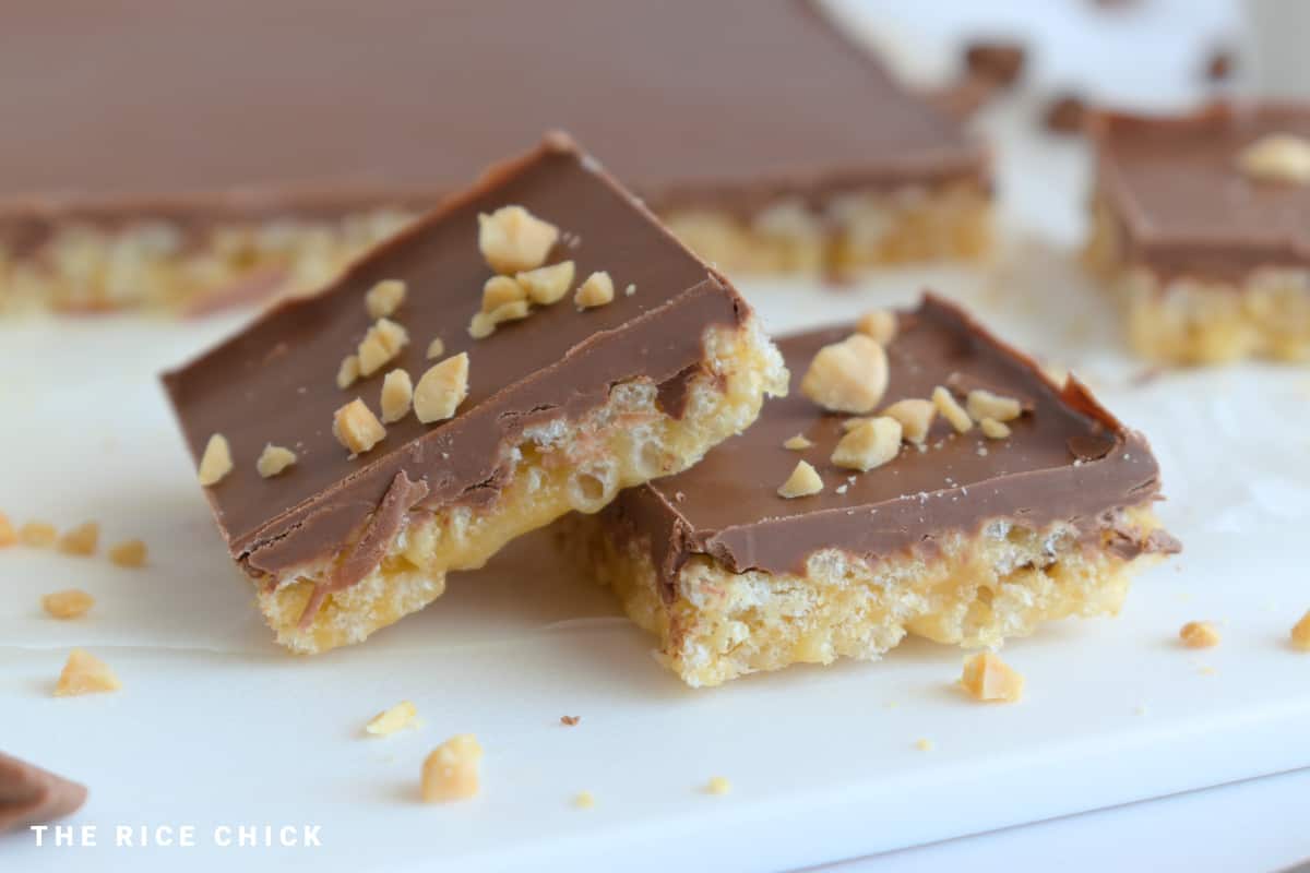 Two slices of chocolate peanut butter rice krispie treats with chopped peanuts on top.