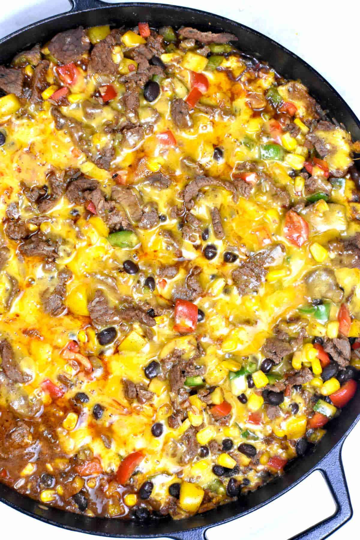Mexican casserole with melted cheese on top in a skillet.