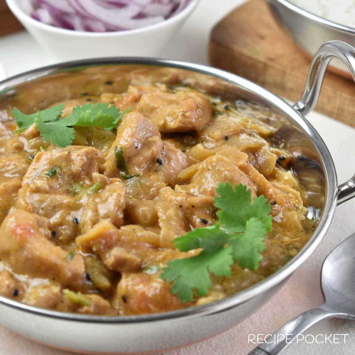 Close up image of Balti chicken in a metal serving bowl.