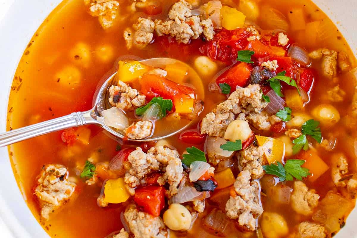 Close up image of ground turkey soup in a bowl with a spoon.