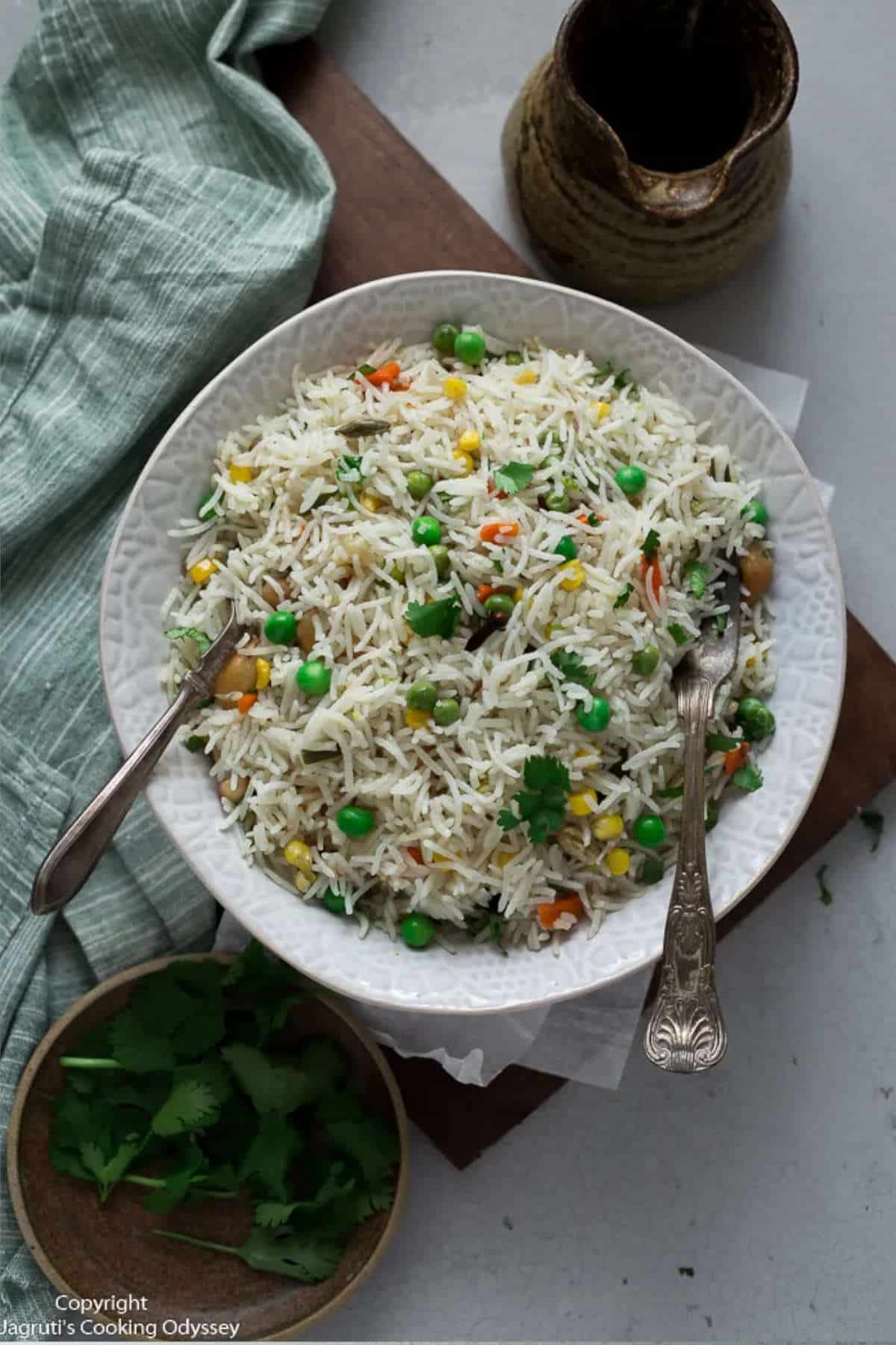 Instant pot pulao on a white plate with a spoon and fork.