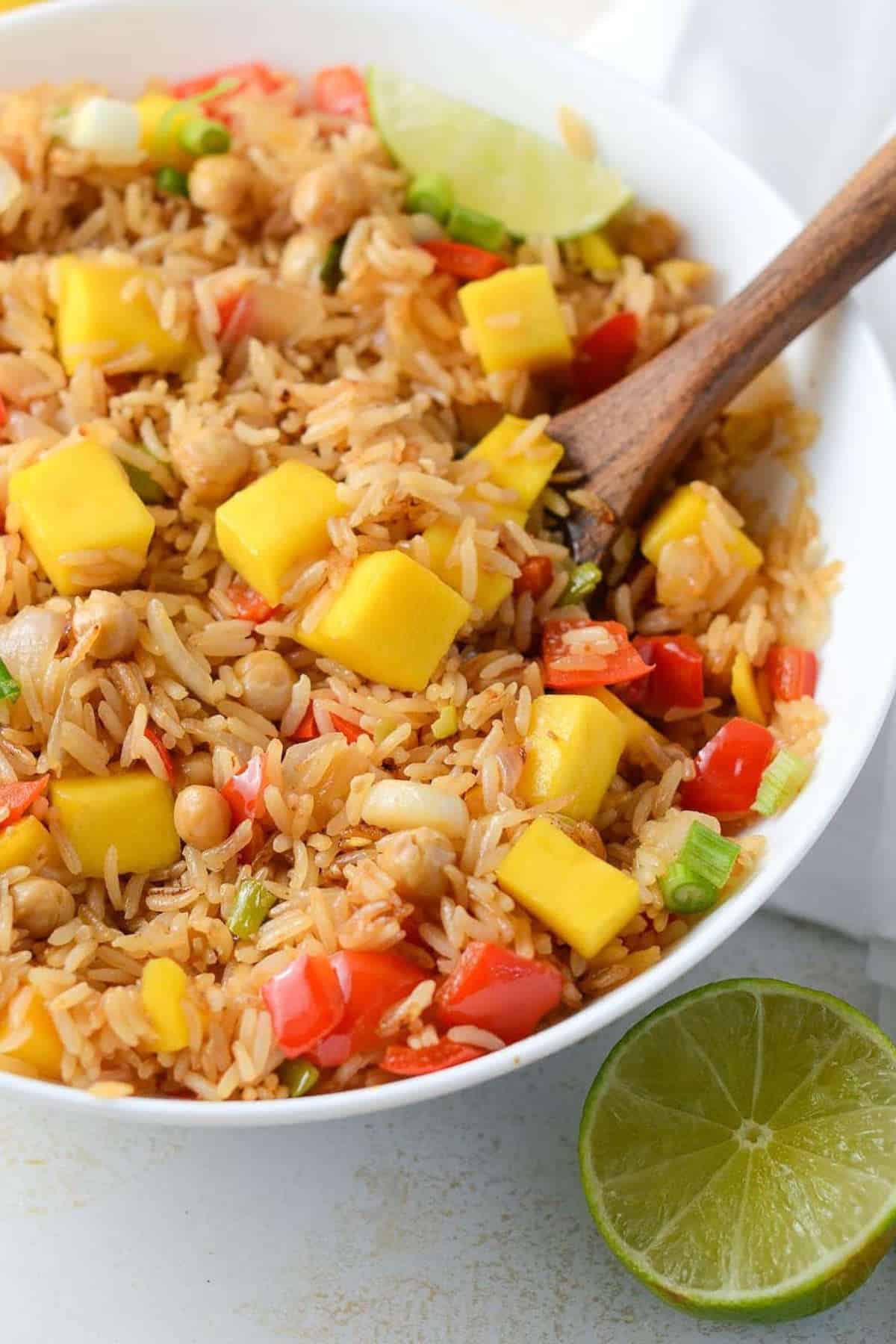 Close up image of mango fried rice with a wooden spoon.