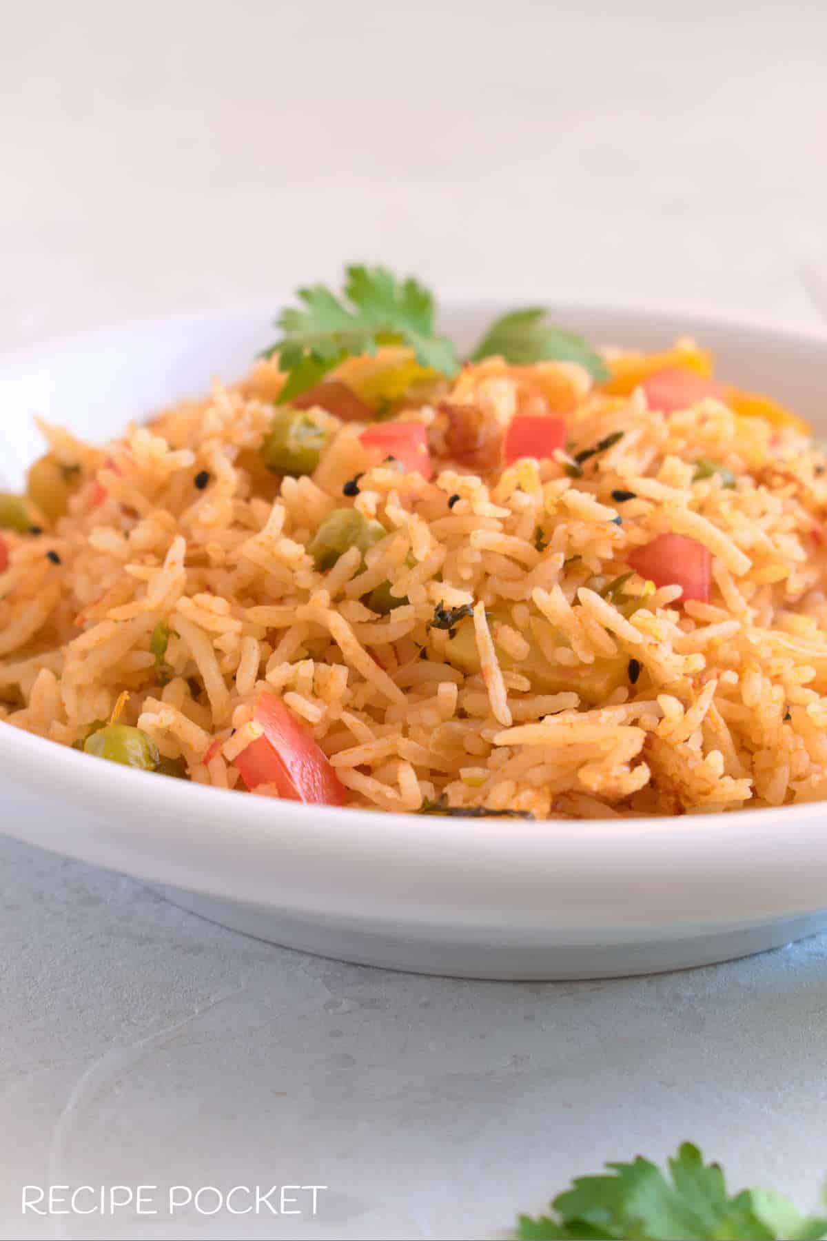 Tomato pulao in a white bowl garnished with coriander leaves.