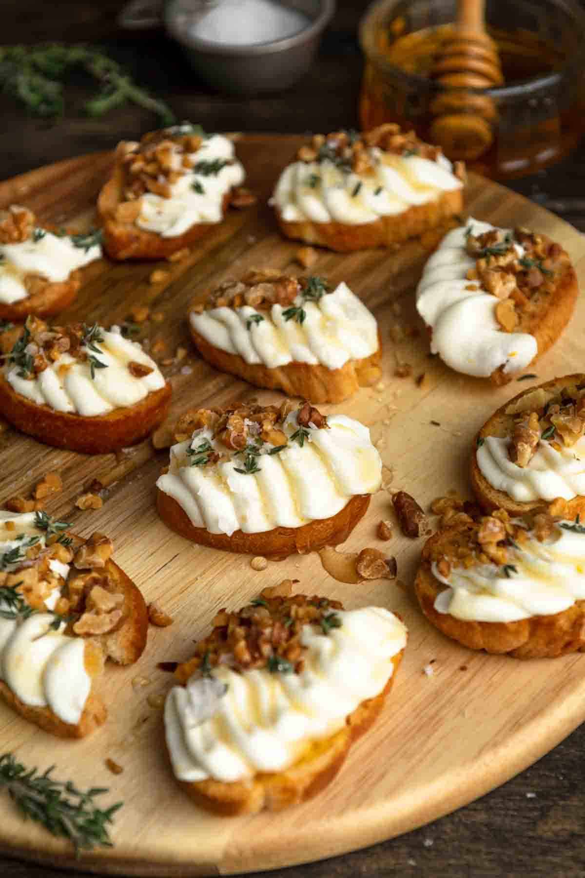Whipped ricotta on crostini on a wooden board.