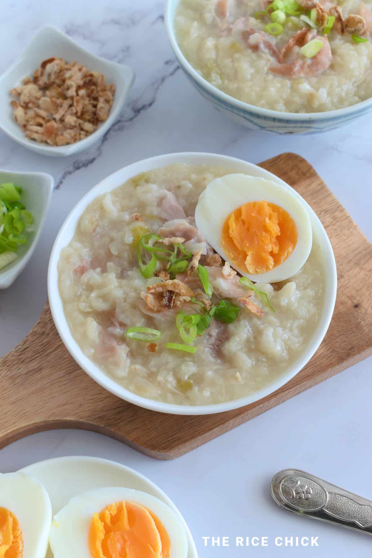 Rice porridge in a white bowl on a wooden board.