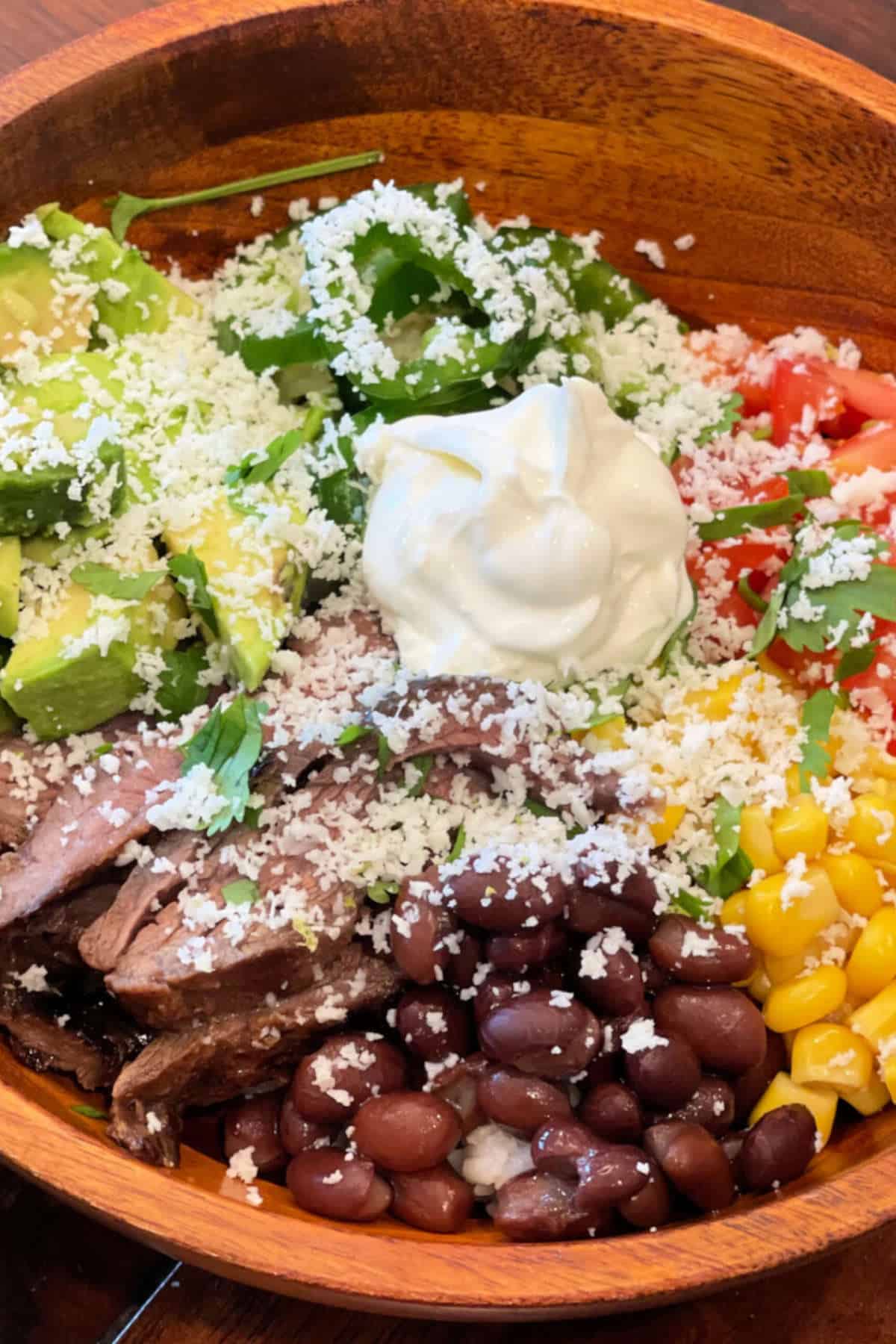 Close up image of burrito bowl in a wooden bowl.