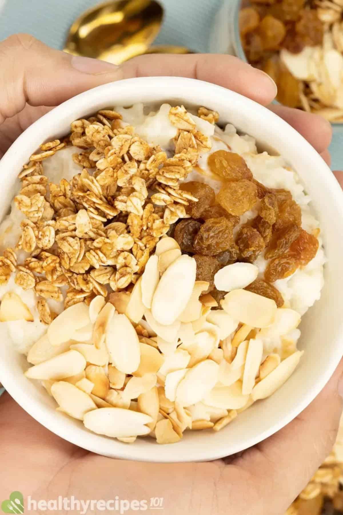 Close up image of rice pudding in a bowl with almonds, oats, and raisins.