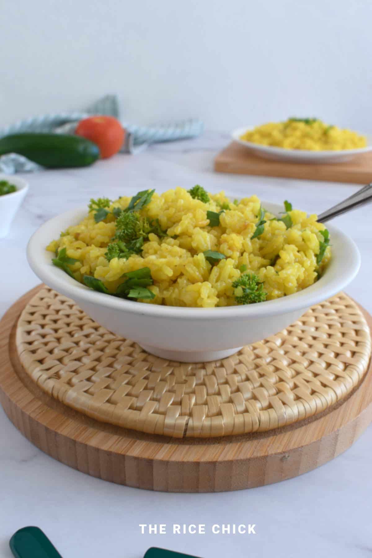 Yellow rice with chopped herbs in a bowl.