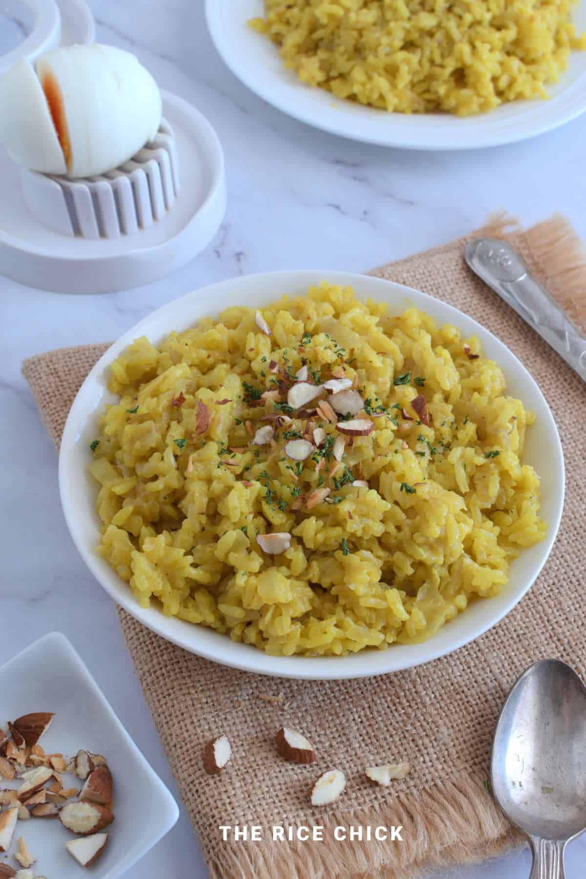 Close up image of yellow rice with chopped nuts on top.