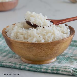 A bowl of basmati rice with a wooden spoon on top of the rice.