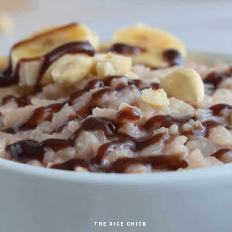 Close up image of Nutella rice flakes porridge topped with chocolate sauce, sliced banana, and chopped nuts.