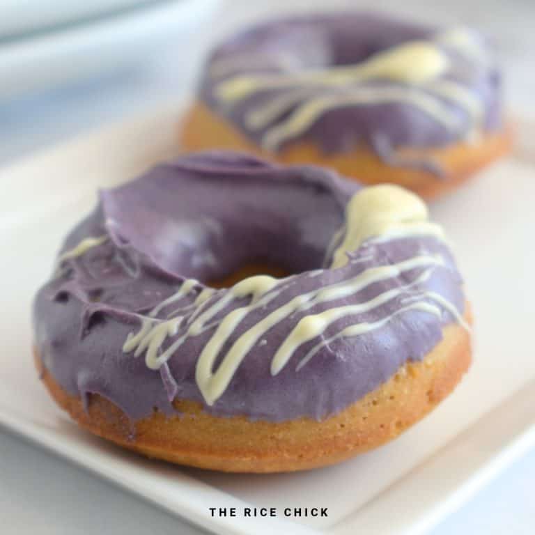 Two ube glazed mochi donuts on a white plate.
