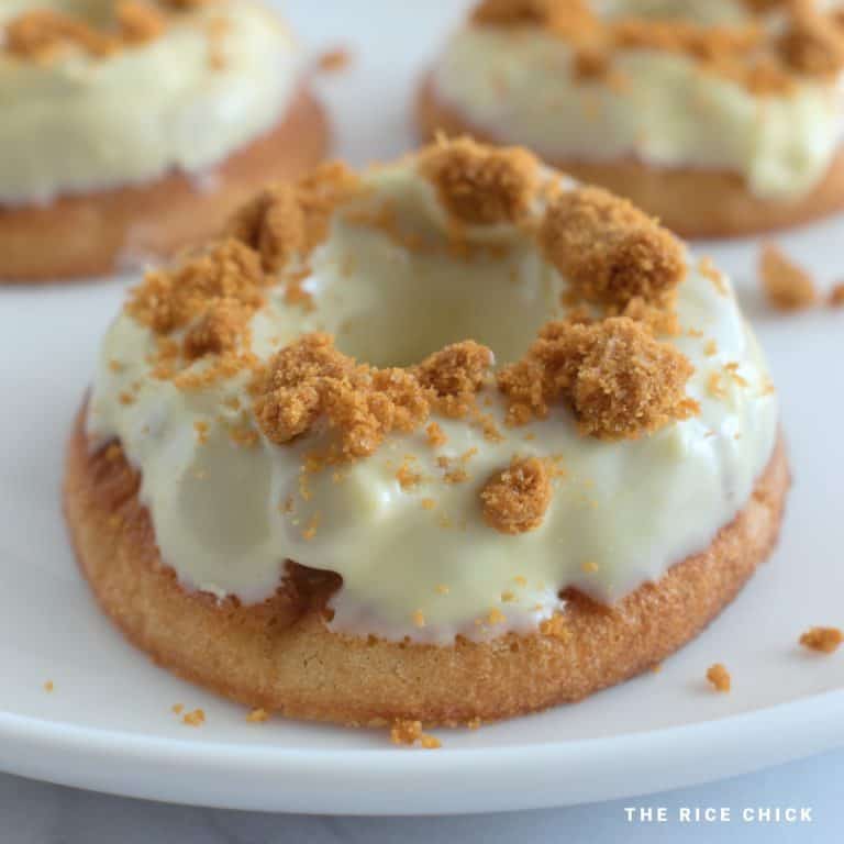 White chocolate glazed mochi donut with biscuit crumbs on top.