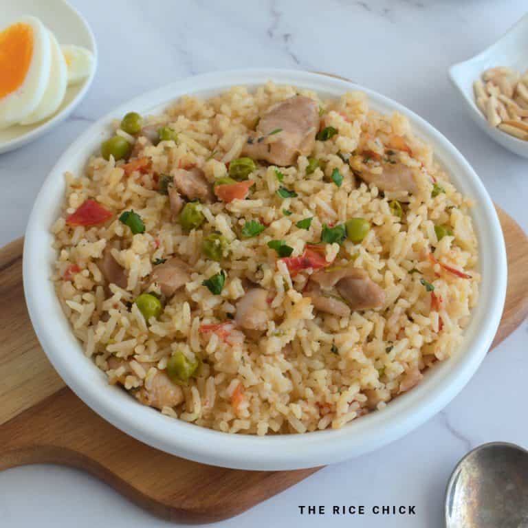 Close up image of pulao with chicken in a white bowl.