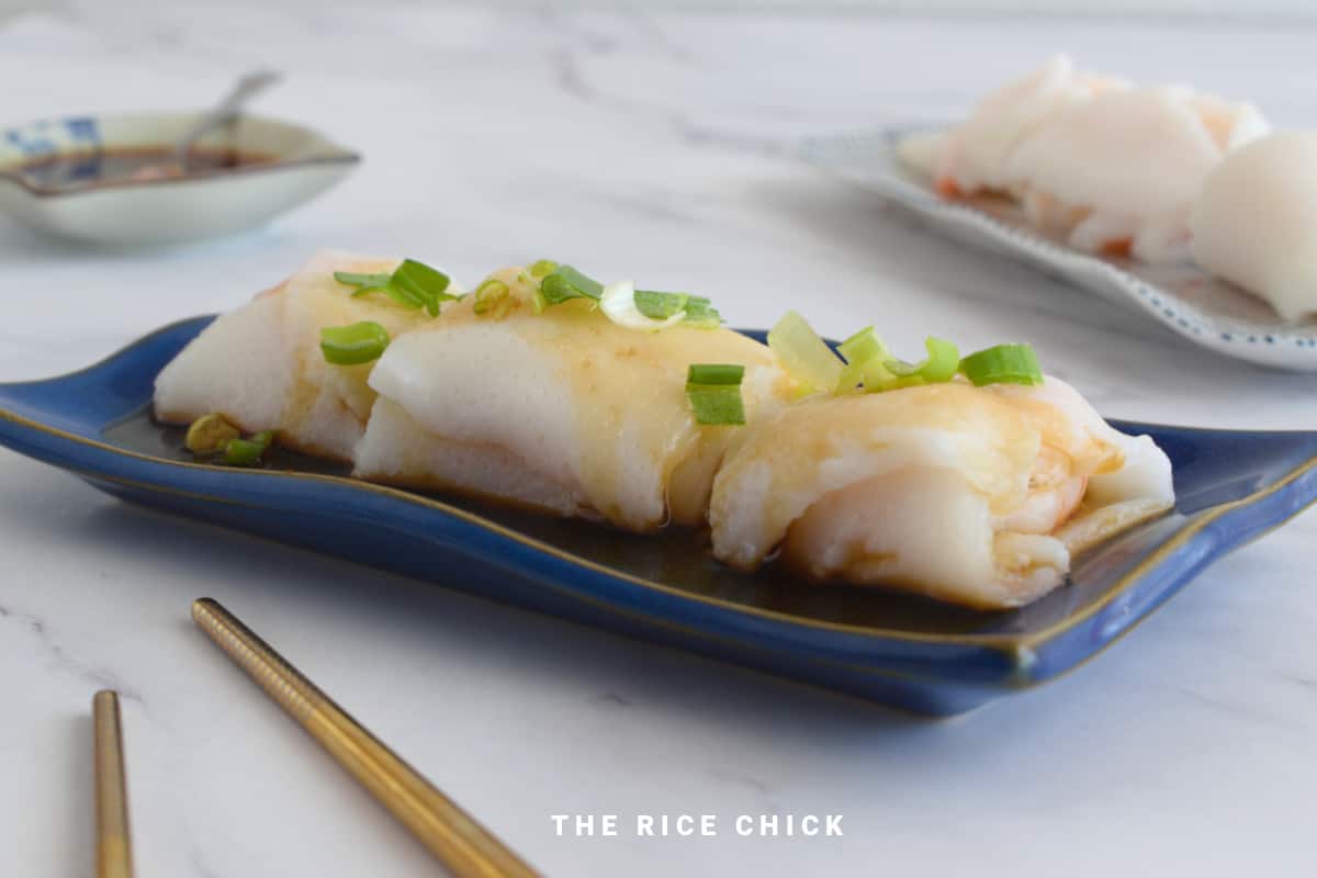 Close up image of steamed rice rolls on a blue plate.