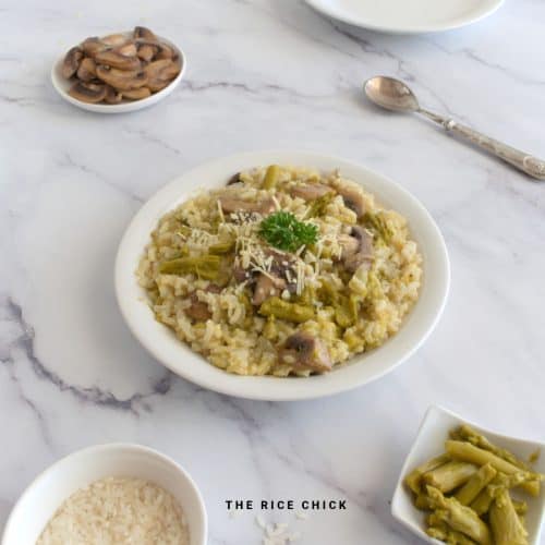 Risotto with asparagus and mushrooms in a white bowl.